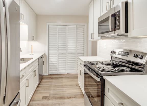 a kitchen with white cabinets and stainless steel appliances and a refrigerator at The Oliver Apartment Homes, Olive Branch, MS, 38654
