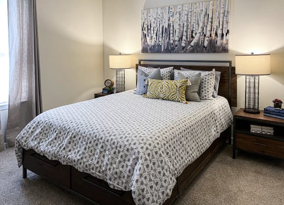 a bedroom with a bed and a painting on the wall at The Madison Apartment Homes in Tyler, TX 75703