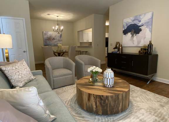 A living room with a grey couch, a wooden coffee table, and a painting on the wall.