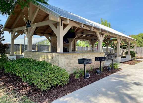 A covered walkway with a stone wall and mailboxes.