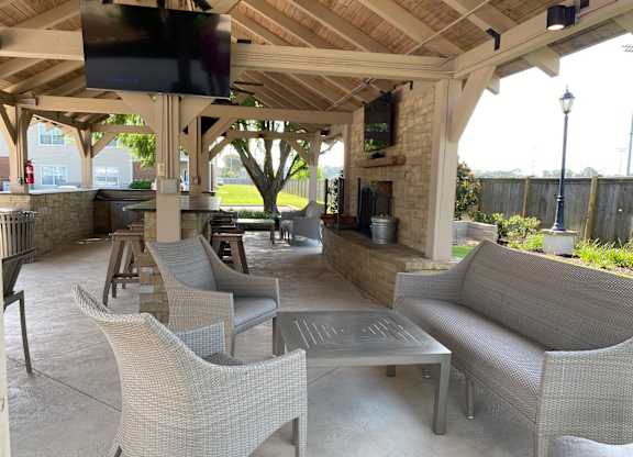A patio with a television mounted on the ceiling and several chairs and tables.