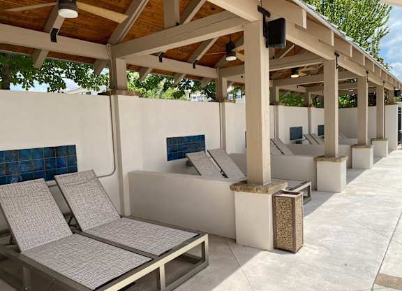 A row of sun loungers are lined up under a wooden roof.