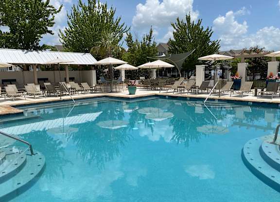 A large swimming pool surrounded by lounge chairs and umbrellas.