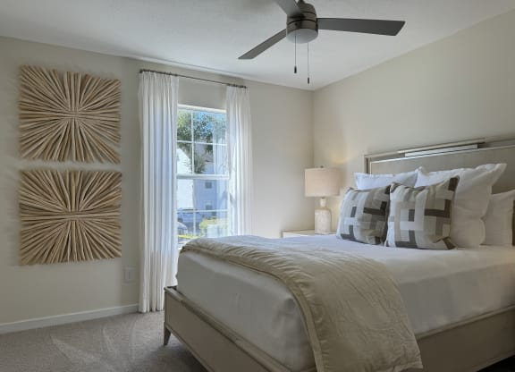 a bedroom with a large bed and a ceiling fan at The Vineyard at Castlewoods Apartment Homes in Brandon, Mississippi