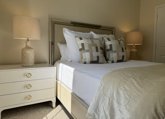a bedroom with a bed and two lamps at The Vineyard at Castlewoods Apartment Homes in Mississippi 39047