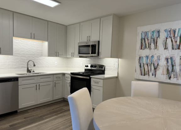 a kitchen with white cabinets and a table and chairs at The Vineyard at Castlewoods Apartment Homes in Brandon, MS 39047