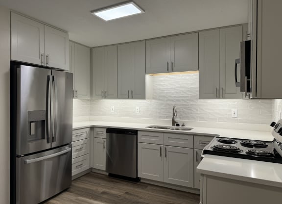 a kitchen with white cabinets and a stainless steel refrigerator at The Vineyard at Castlewoods Apartment Homes in Brandon, Mississippi 39047
