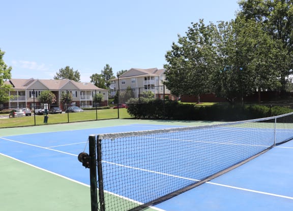a tennis court with apartments in the background at Reserve at Park Place Apartments, Mississippi 39402