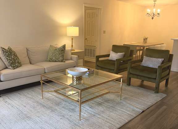 A living room with a glass coffee table and a white sofa.