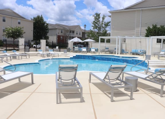 a swimming pool with lounge chairs and umbrellas at a apartment complex at Reserve at Park Place Apartments, Mississippi