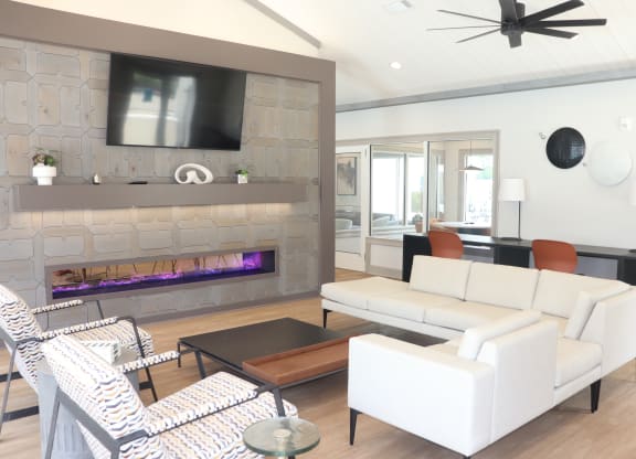 a living room with white furniture and a stone fireplace at Reserve at Park Place Apartments, Hattiesburg, MS