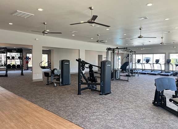 A gym with a variety of equipment including treadmills, weights, and exercise machines.