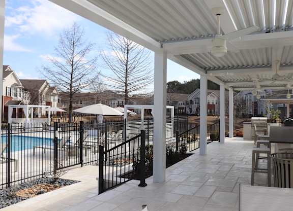 A patio with a pool and a black fence at Carlton Park Apartment Homes in Flowood, MS