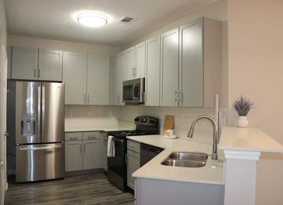 A kitchen with a stainless steel refrigerator and a white countertop at Carlton Park Apartment Homes in Flowood, MS