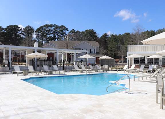 A pool with chairs and umbrellas at carlton park apartment homes in flowood, ms