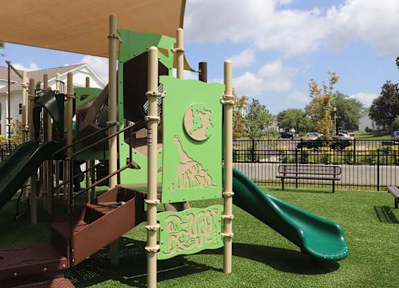 A playground with a green slide and a sign that says "Frog".