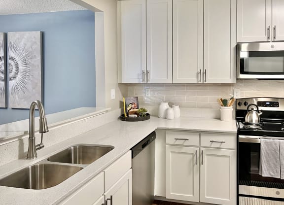 a modern kitchen with white cabinets and stainless steel appliances at Reserve at Park Place Apartments, Mississippi