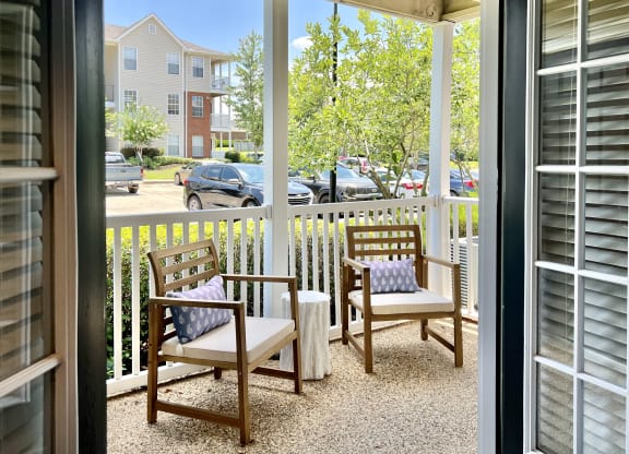 a porch with two chairs and a table and a fence at Reserve at Park Place Apartments, Hattiesburg, 39402