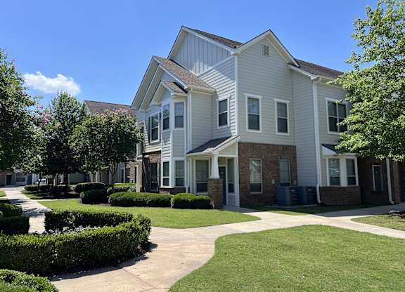 A residential building with a white facade and a green lawn in front at Audubon Park Apartments in Zachary, LA