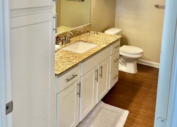 A bathroom with a sink, toilet, and cabinets.