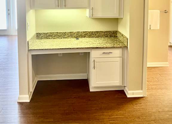 A kitchen with white cabinets and a granite countertop.