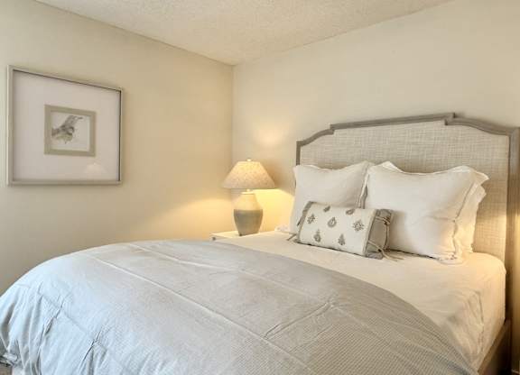 A bed with white pillows and a grey headboard is in the image at The Pointe Apartment Homes, Gautier, 39553