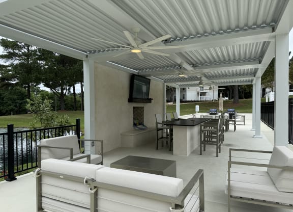 a covered patio with white furniture and a television at Laurelwood Apartment Homes, Mississippi