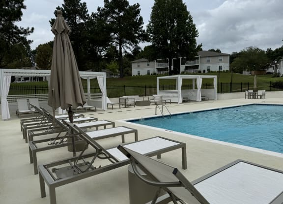 a swimming pool with chairs and an umbrella next to it at Laurelwood Apartment Homes, Mississippi, 39440