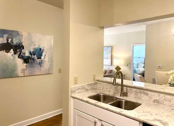 A kitchen with a marble countertop and a painting on the wall.