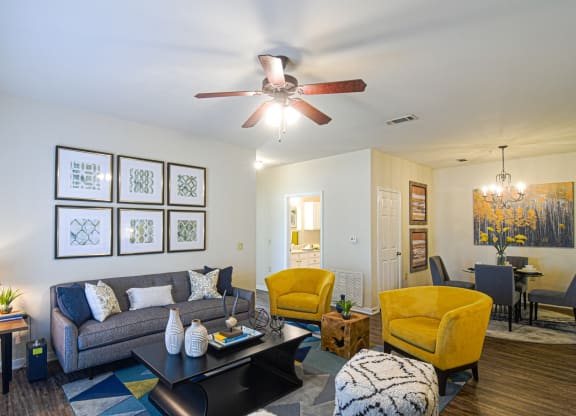 a living room with a ceiling fan and a couch at The Madison Apartment Homes in Tyler, TX  