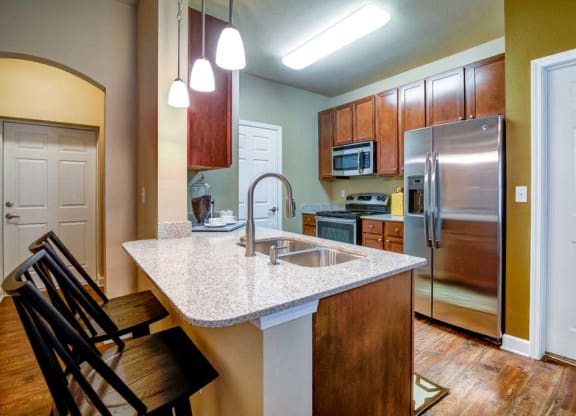 a kitchen with a granite counter top and a stainless steel refrigerator at The Retreat Apartment Homes in Williston, 58801