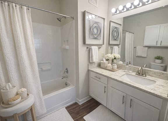 A white bathroom with a shower, sink, and toiletries.