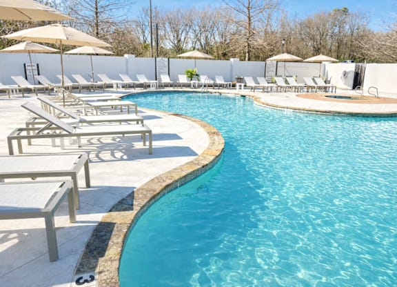 A large swimming pool surrounded by sun loungers and umbrellas.