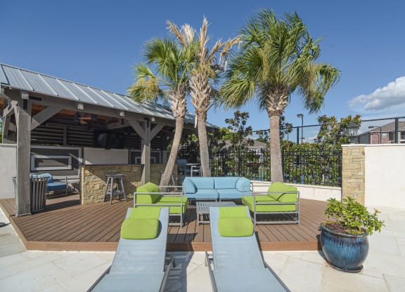 a patio with couches and chairs and palm trees at Canebrake Apartment Homes, Louisiana