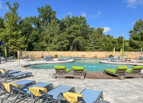 a pool with chairs and tables and a swimming pool with trees at The Madison Apartment Homes in Tyler, TX 75703