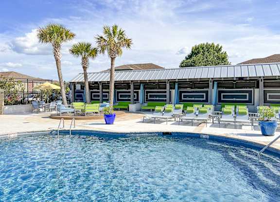 A pool with a metal roof and a few chairs and plants at Canebrake Apartment Homes in Shreveport