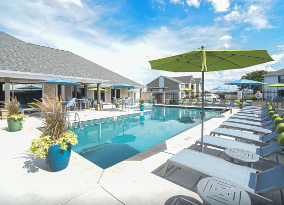 a swimming pool with lounge chairs and umbrellas at the resort at Reserve of Bossier City Apartment Homes in Bossier City, LA 
