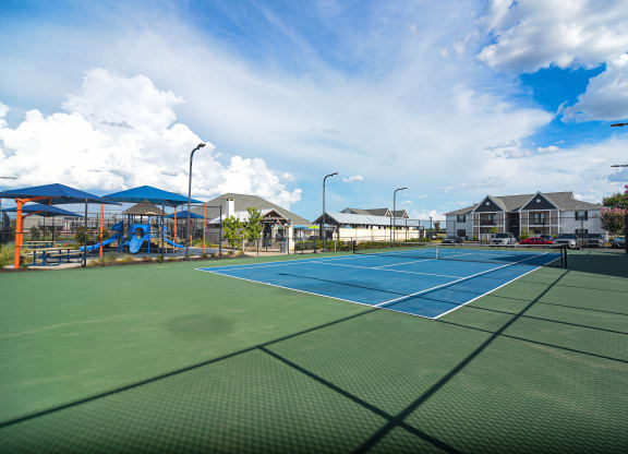 two tennis courts with houses and a playground in the background at Reserve of Bossier City Apartment Homes in Bossier City, Louisiana 71111