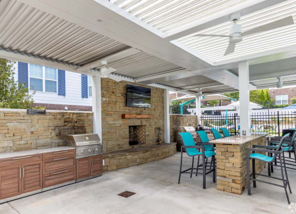 a covered patio with a grill and a table with chairs at The Met Apartment Homes, Mississippi