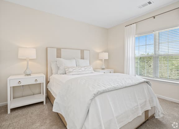 a bedroom with a large bed and a window at The Met Apartment Homes, Hattiesburg, MS, 39402