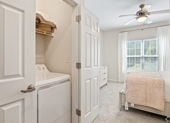 a laundry room with a closet and a bed and a ceiling fan at The Met Apartment Homes, Hattiesburg, MS