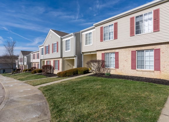 a row of houses with red shuttered windows on a sidewalk