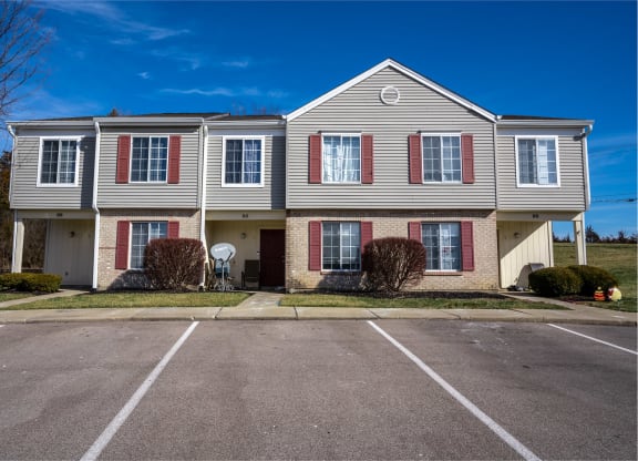a large white house with red shutters and a parking lot