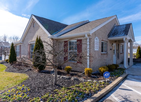 a small brick house with a driveway and landscaping