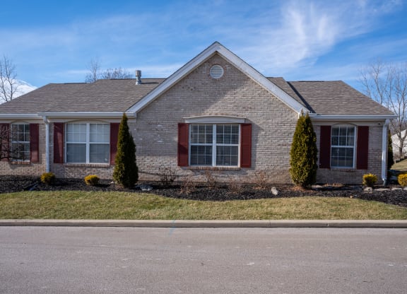 a brick house with red shutters and a blue sky