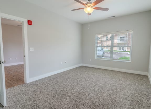 an empty living room with a ceiling fan and a window