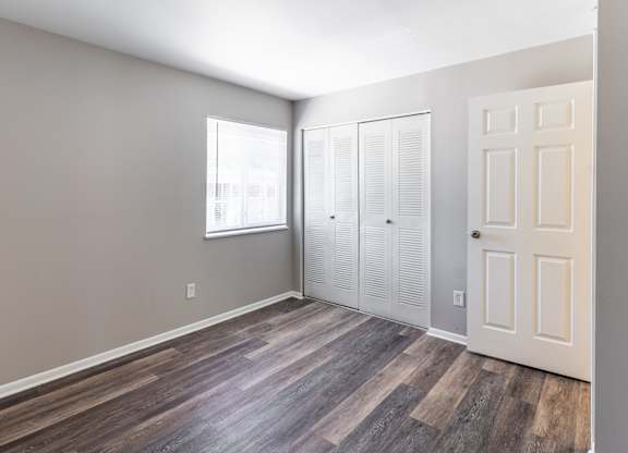 an empty room with wood flooring and white closet doors at Pickwick Farms Apartments, Indiana