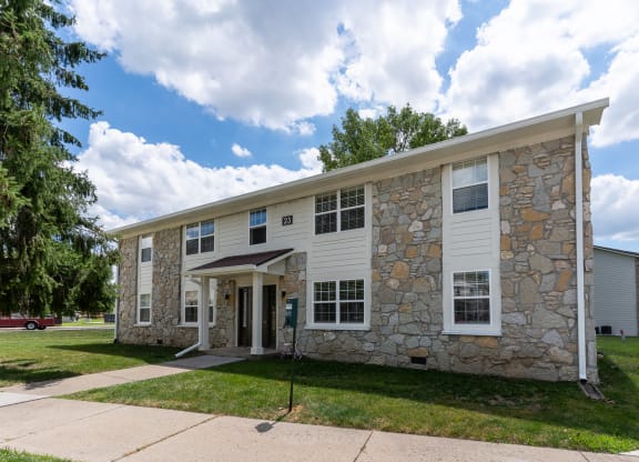 a stone and white building with a sidewalk and grass