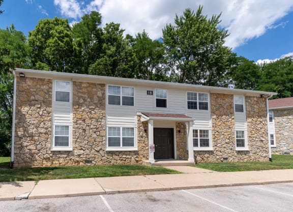 a white building with a stone facade and a sidewalk
