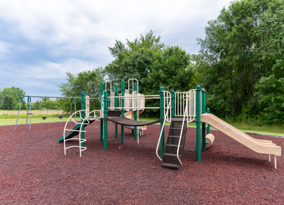 a playground with a slide and chairs in a park